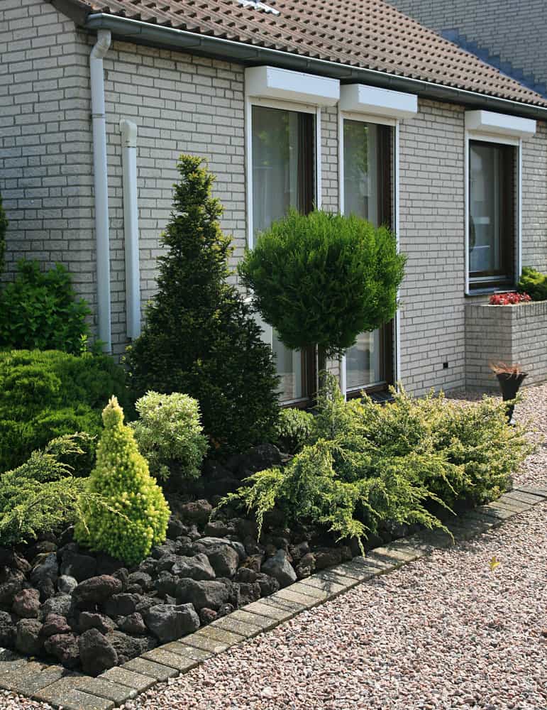 Front garden with mixed shrubs and brick house