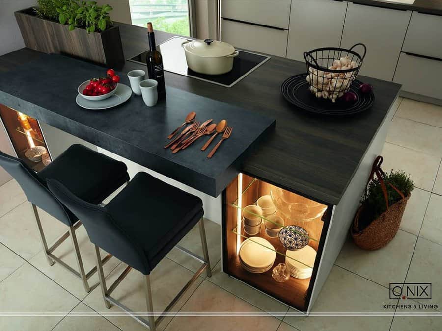 Sleek kitchen with a dark breakfast bar attached to the island, featuring illuminated storage, modern barstools, and stylish table settings