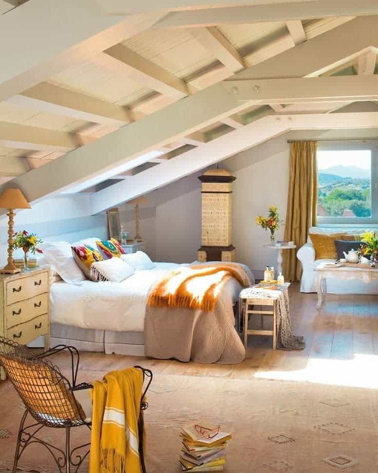 Cozy attic bedroom with exposed beams, warm textiles, and rustic decor. Earthy tones and natural light create a relaxing retreat.