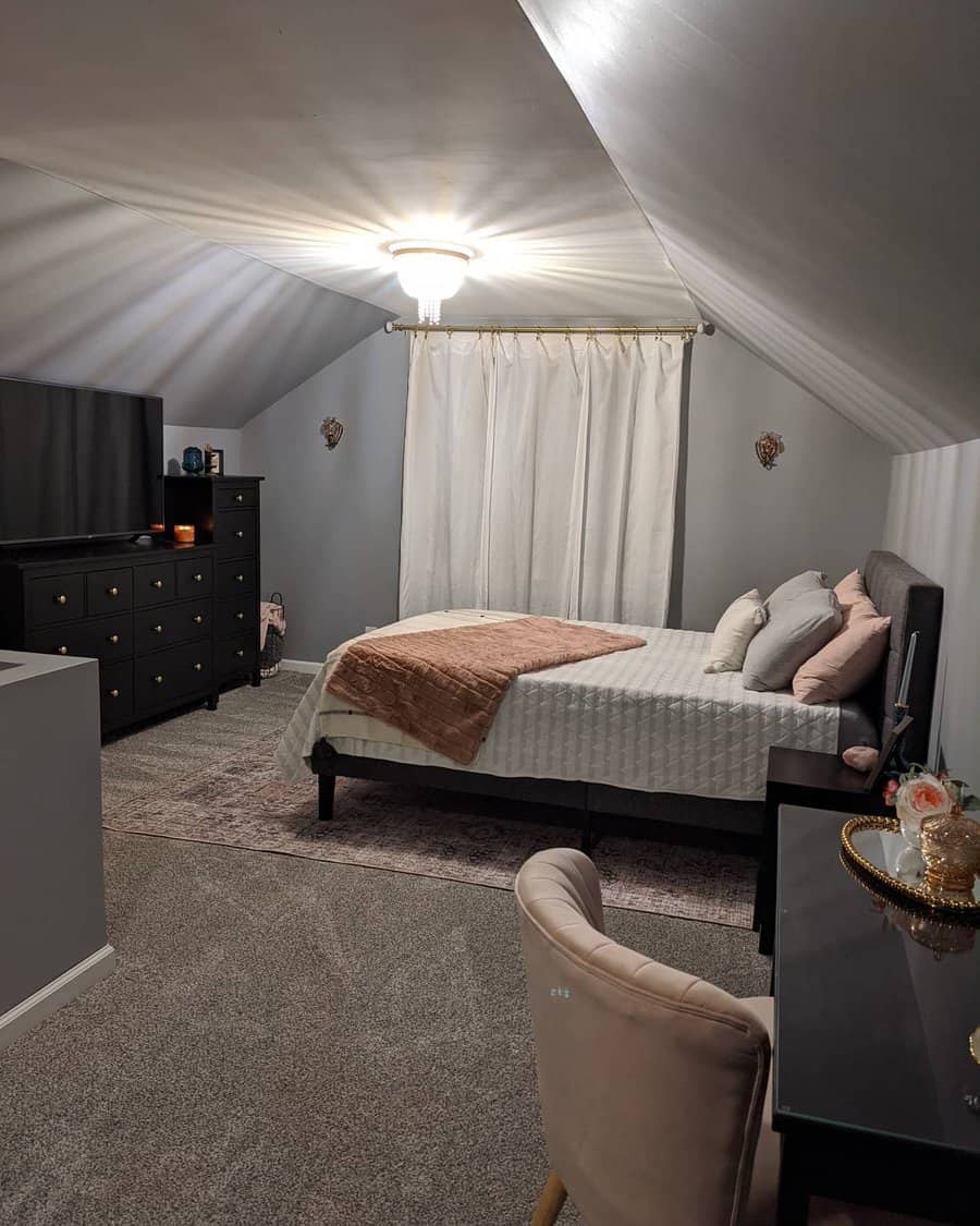 Modern attic bedroom with soft gray walls, plush textures, and elegant black furniture. Warm lighting and blush accents create a cozy retreat.