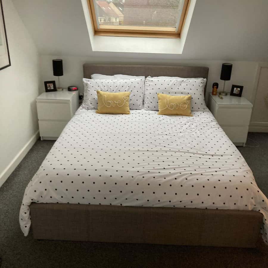 Minimalist attic bedroom with a skylight, polka dot bedding, and soft yellow accents. A bright, cozy space with simple and modern decor.