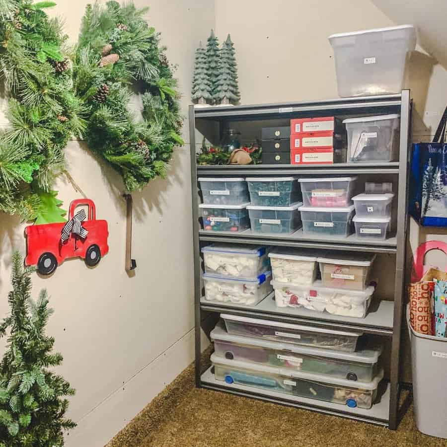 Holiday decor neatly stored in labeled plastic bins on metal shelves in an attic, with wreaths and festive decorations on the wall.