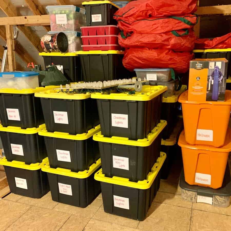 Labeled storage bins neatly stacked in an attic, organizing Christmas and Halloween decorations for easy access and seasonal use.