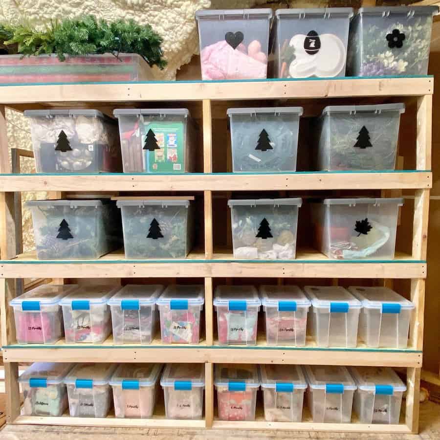 Clear plastic bins with seasonal decorations neatly arranged on wooden shelves in an attic for efficient and organized storage.