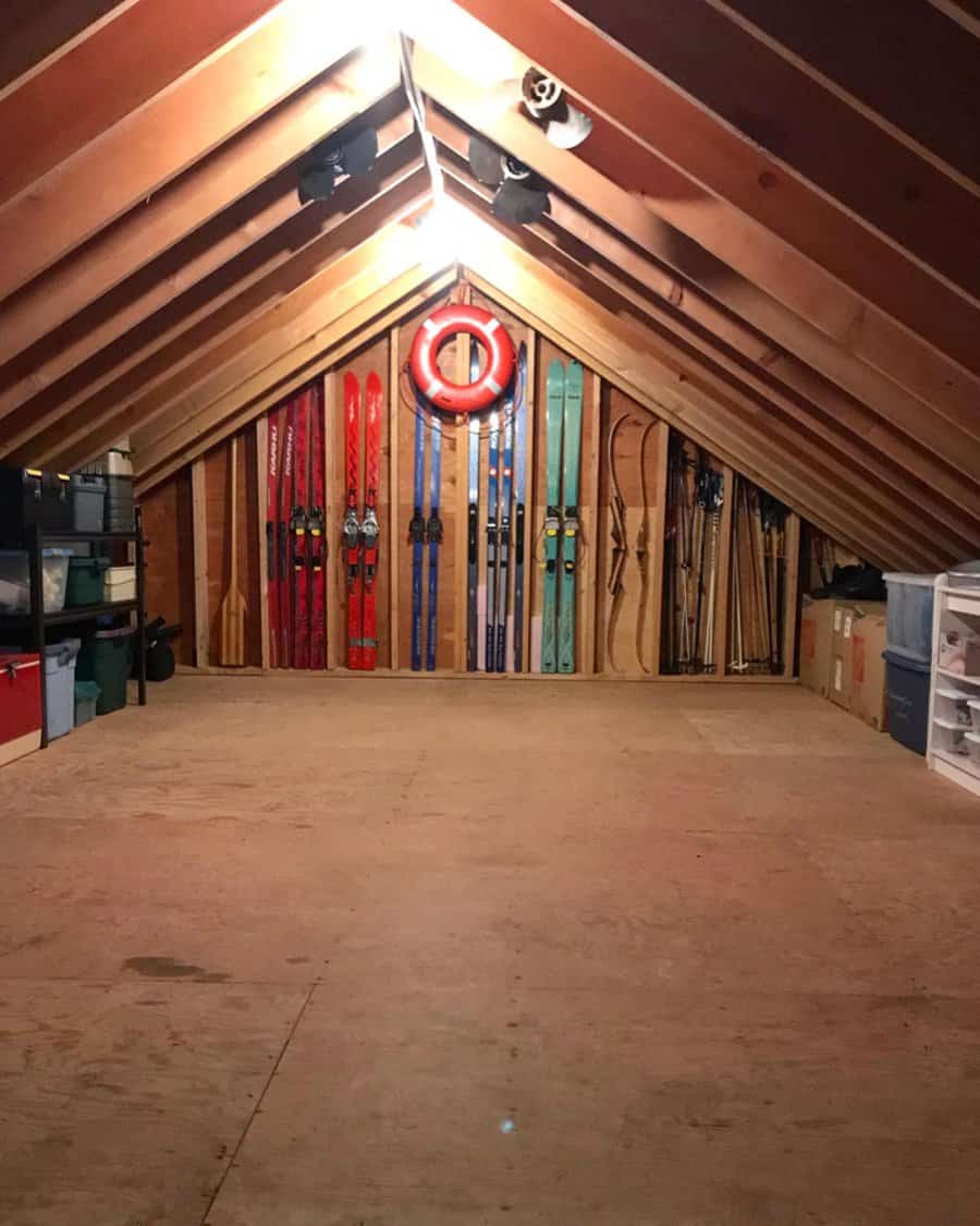 Neatly organized attic with skis mounted on the wall, storage bins on shelves, and open floor space for easy access and functionality.