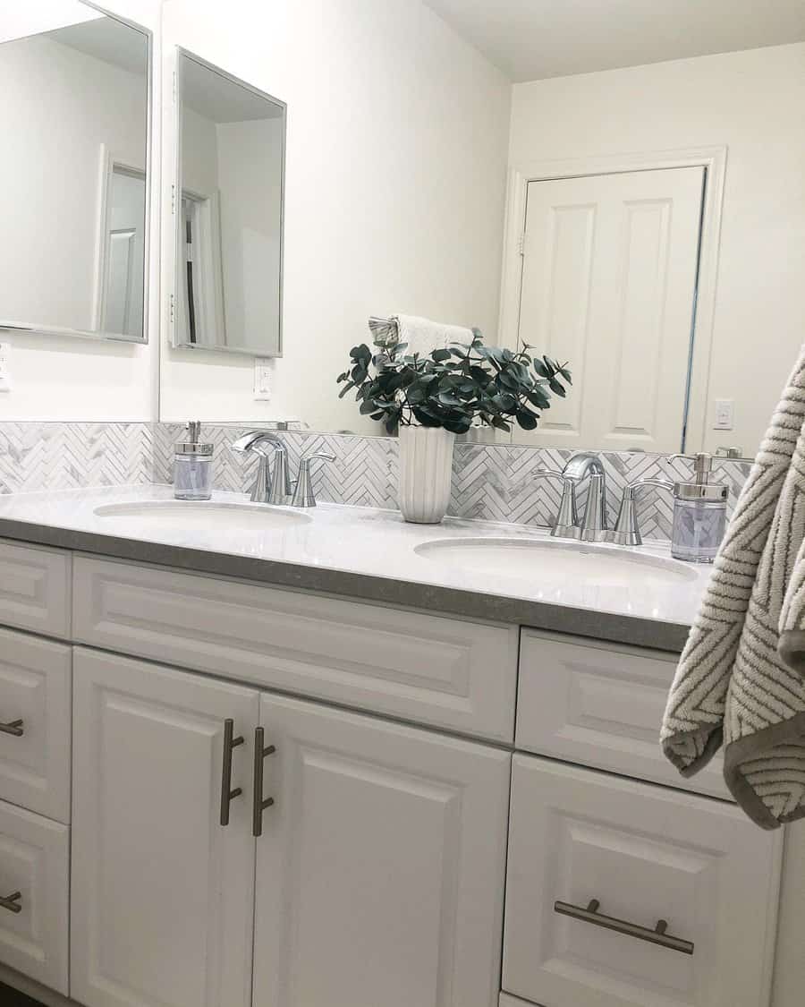 bathroom sink with herringbone tile backsplash