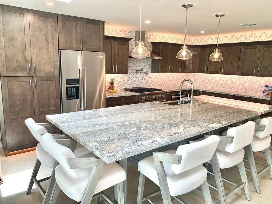 Modern kitchen with a large marble island and wooden cabinets, with pendant lights above