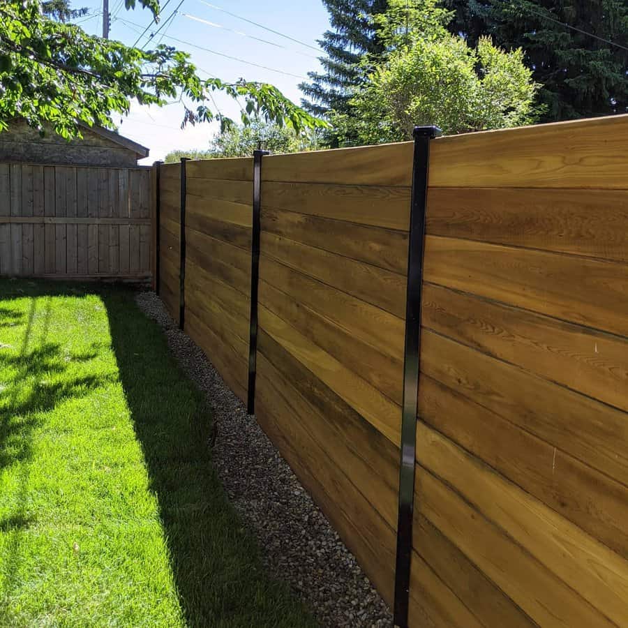 Horizontal wooden fence with metal posts in the backyard