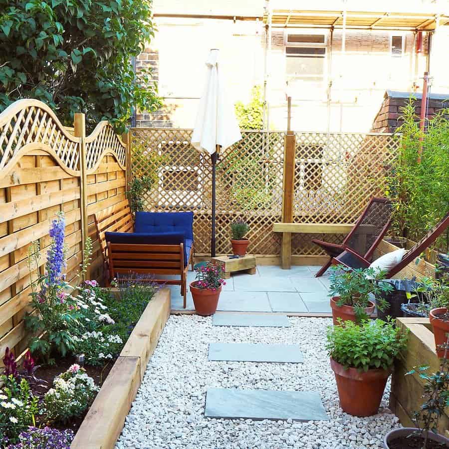 Cozy backyard with a wooden privacy fence, lattice panels, potted plants, and shaded seating areas featuring a bench, chairs, and an umbrella