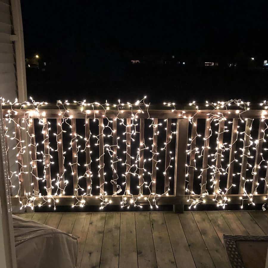 String lights drape over a wooden porch railing, glowing warmly against the night sky