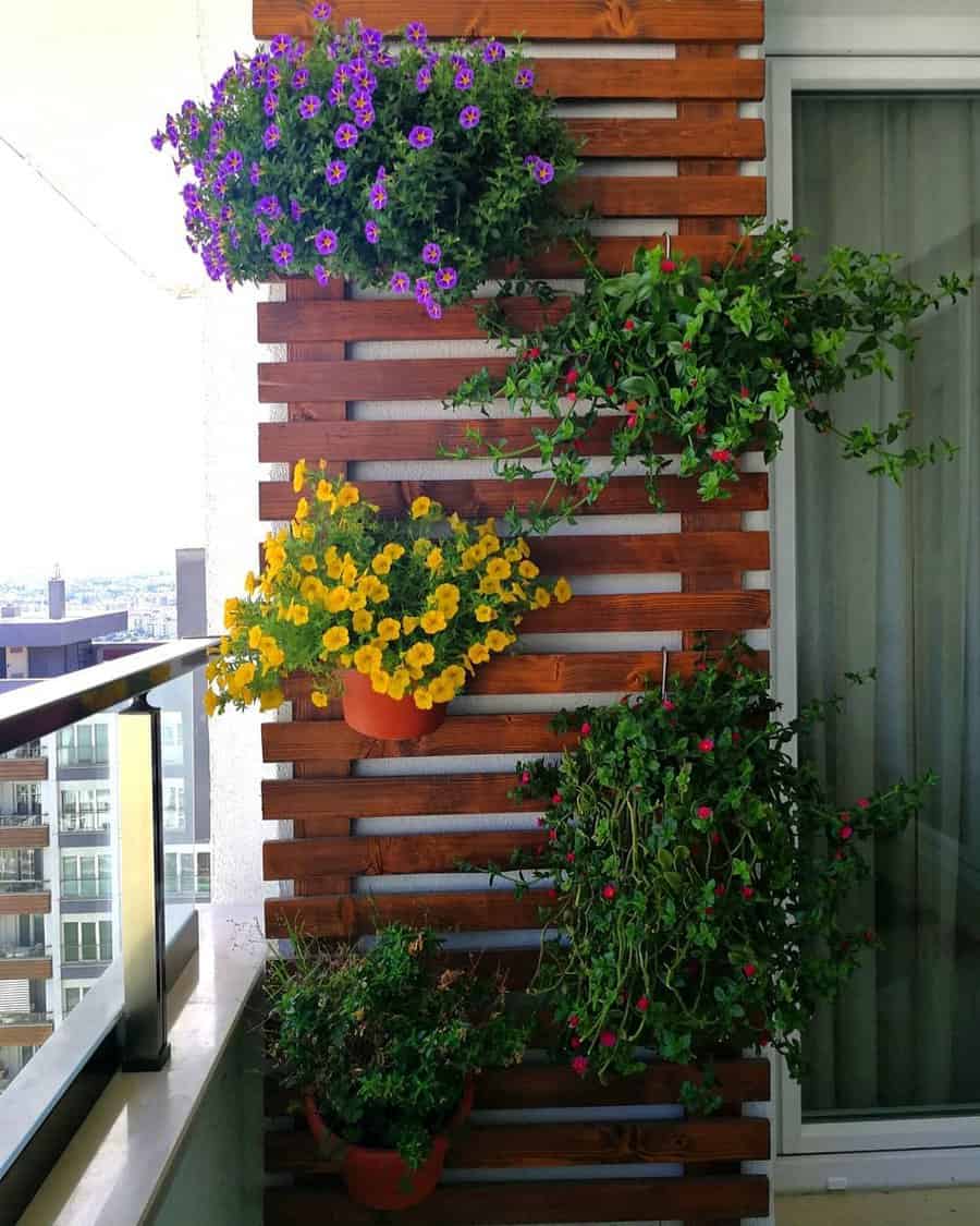 Vertical garden on a balcony with wooden paneling, featuring colorful flowers in pots arranged along the wall