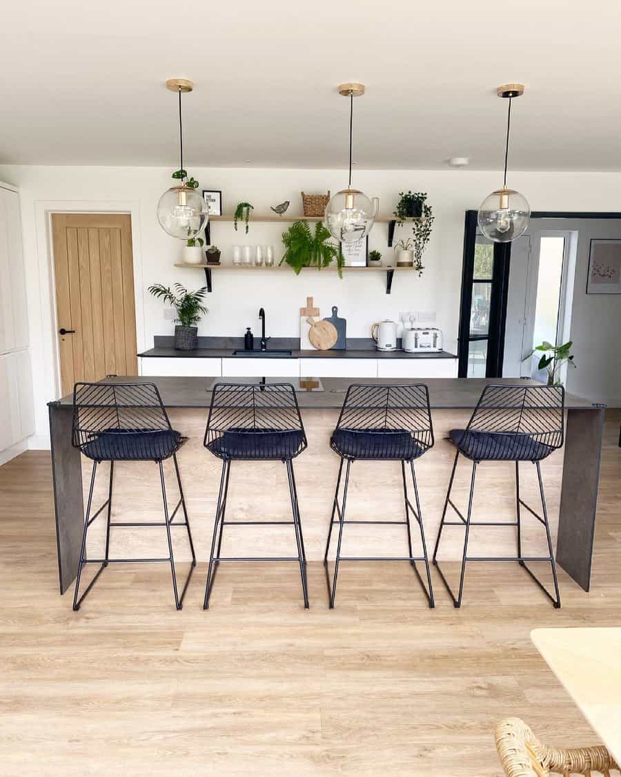 Modern kitchen with black bar stools and pendant lights