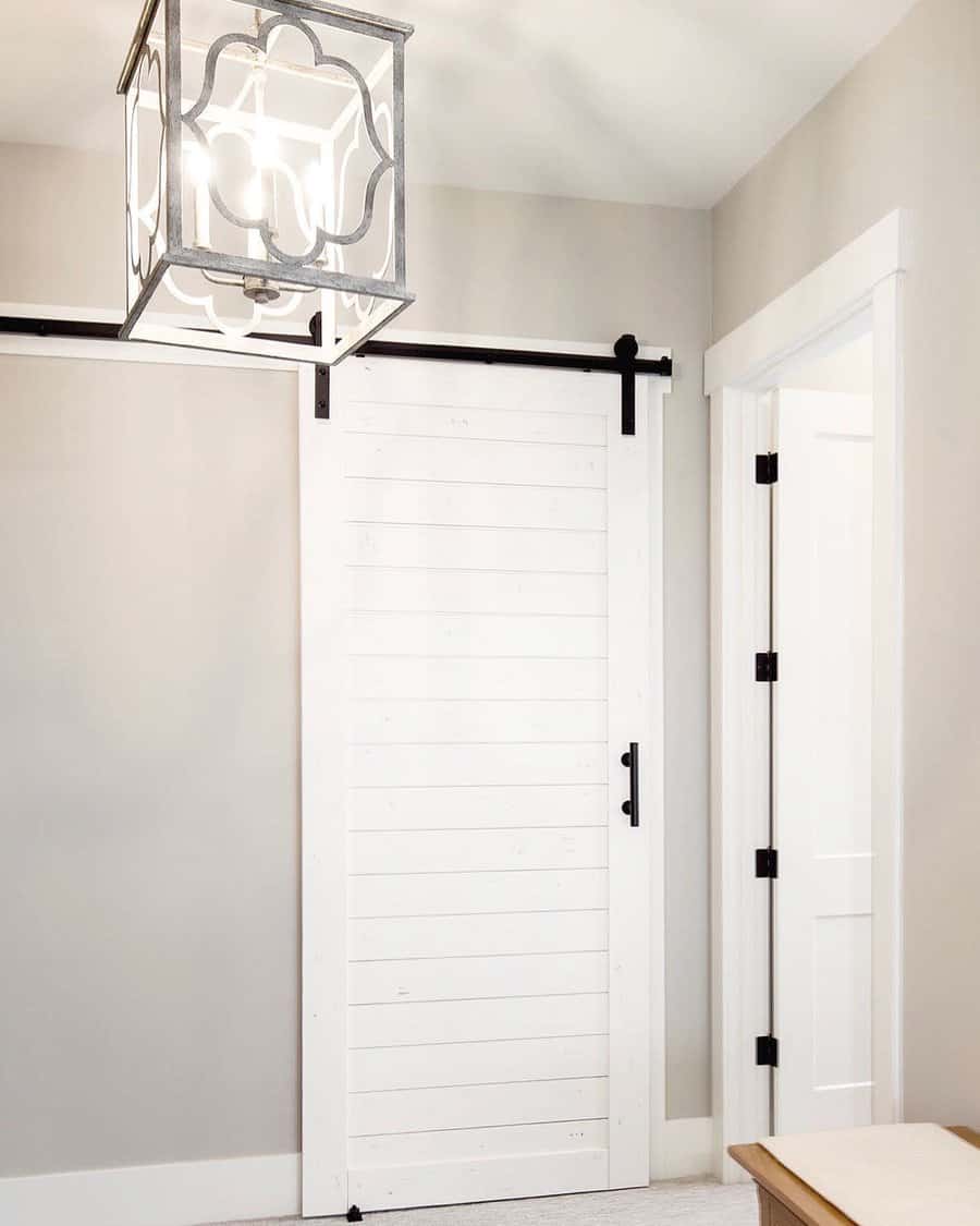 White sliding barn door with black hardware in a bright room, geometric pendant light hangs from the ceiling