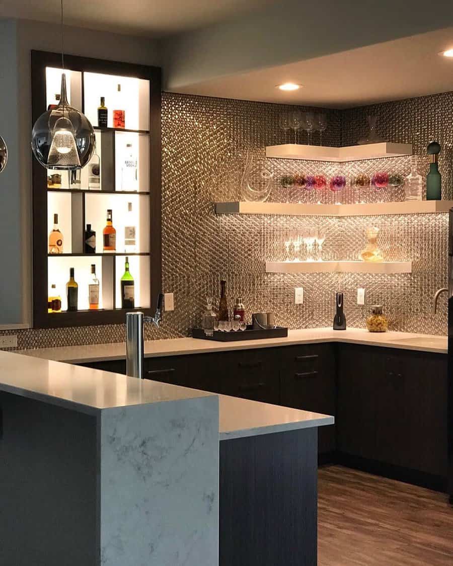 Modern basement bar with a metallic backsplash, illuminated bottle display, sleek cabinetry, and floating shelves for a luxurious ambiance.