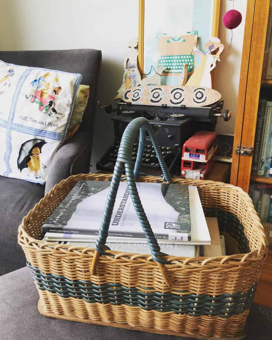 Wicker basket used for book storage on a couch, filled with hardcover books. A vintage typewriter and decor in the background.







