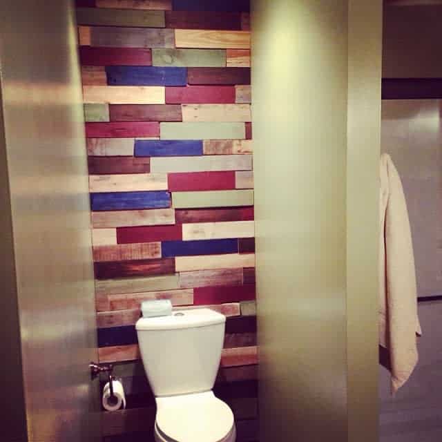 Colorful pallet wood wall behind a white toilet