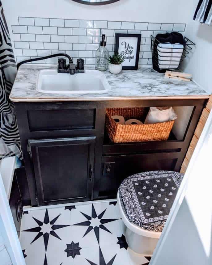 A stylish RV bathroom featuring black and white star-patterned tiles, a marble countertop, and modern accessories.