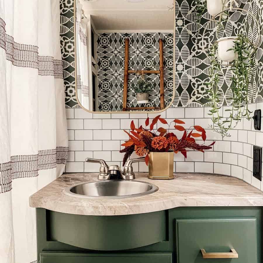 A vibrant RV bathroom with a green vanity, floral tile backsplash, marble countertop, and stylish decor accents like plants and flowers.