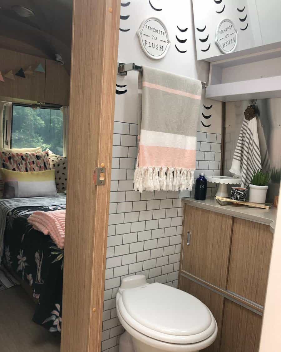 Compact RV bathroom with wood cabinetry, towel storage, and decorative touches, maximizing space with smart storage solutions.