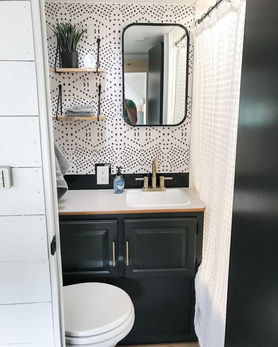 Stylish RV bathroom with black cabinetry, open shelves, and a patterned wall, combining modern design with functional storage.