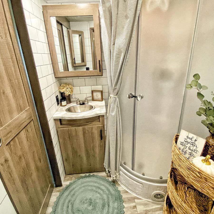 Cozy RV bathroom with wood cabinetry, a compact sink, a curved shower, and woven basket storage, blending rustic charm with functionality.