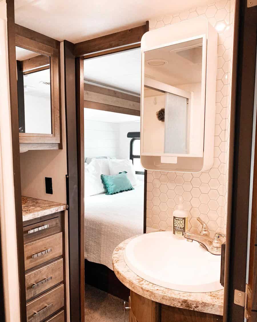 RV bathroom with wood cabinetry, a round sink, a mirrored storage cabinet, and a hex tile backsplash, blending style with smart storage.