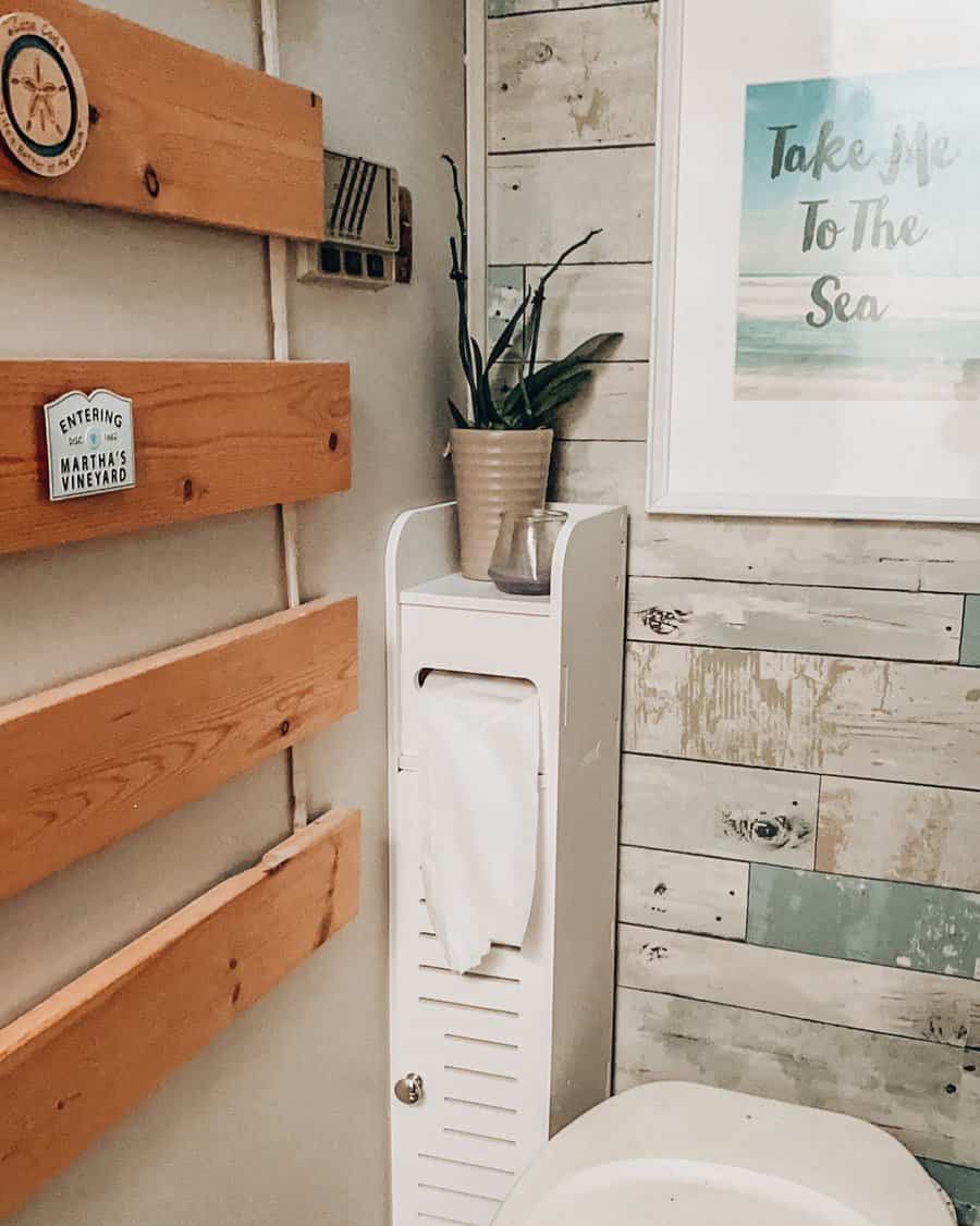 Coastal-style RV bathroom with wood accents, a compact storage cabinet, and beach-themed decor, creating a relaxed and organized space.