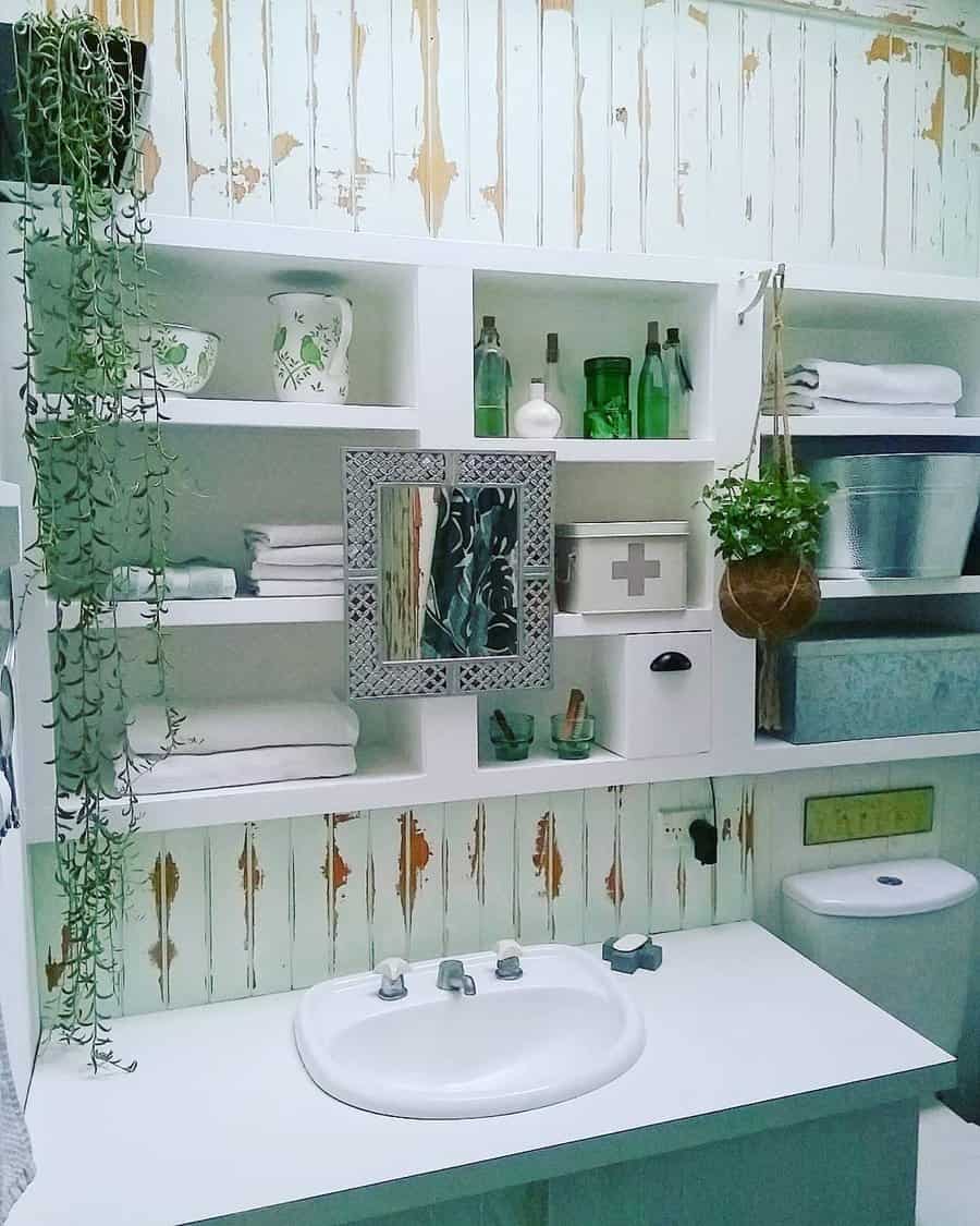 Rustic bathroom with open white shelving for towels, bottles, and décor, featuring hanging plants and a vintage distressed wood wall