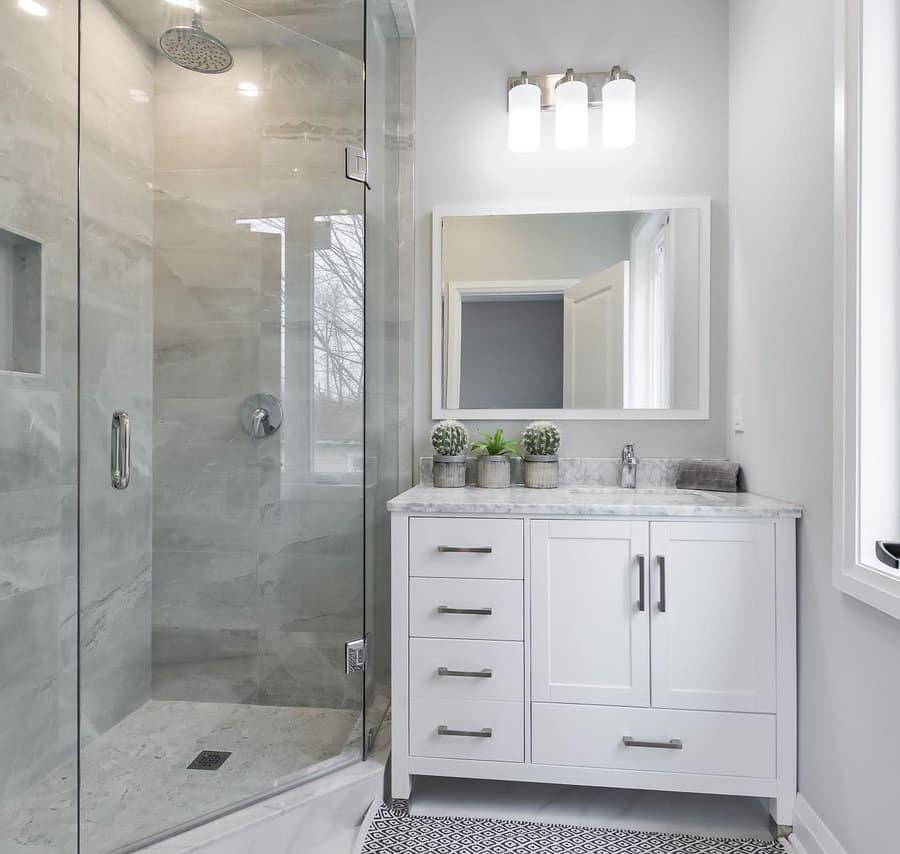 A modern bathroom with a sleek glass shower, a white vanity with ample storage, marble countertops, and minimalist decor for a clean look