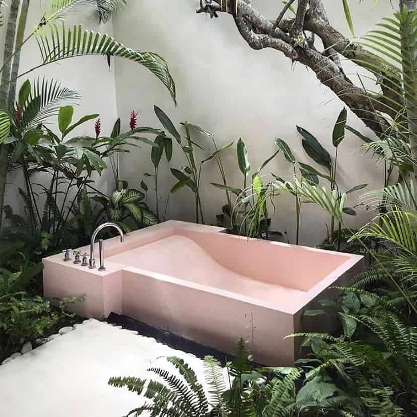 Pink outdoor bathtub in a lush tropical setting, surrounded by green plants for a serene, spa-like escape