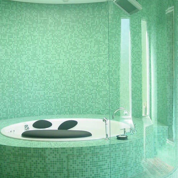 Round bathtub in a tiled green alcove