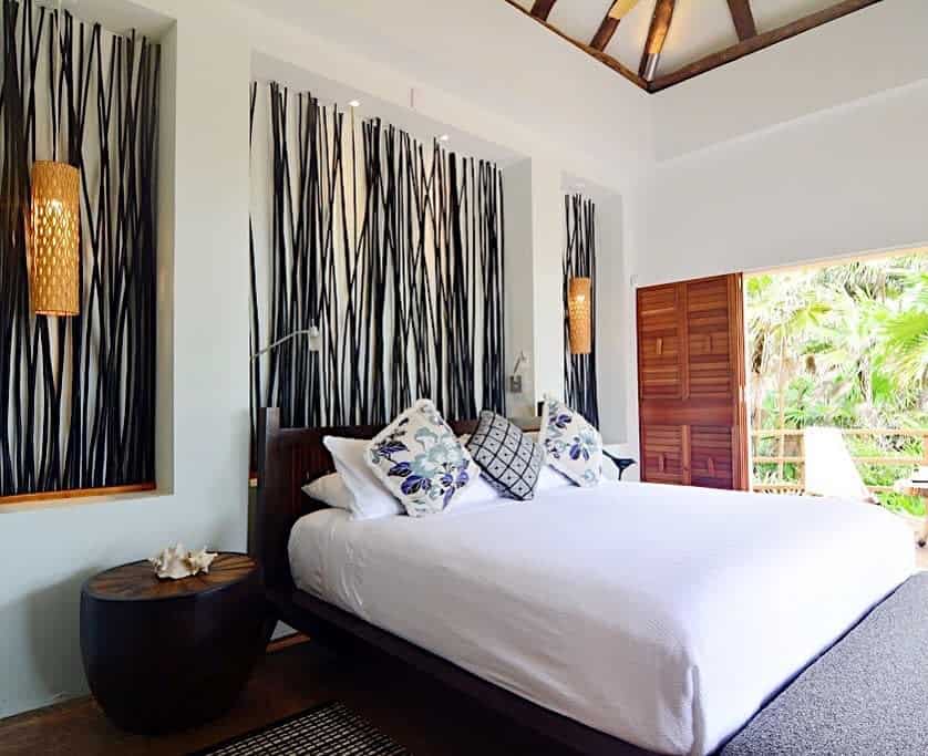 Modern tropical bedroom with a large bed, black and white art, and a lush view