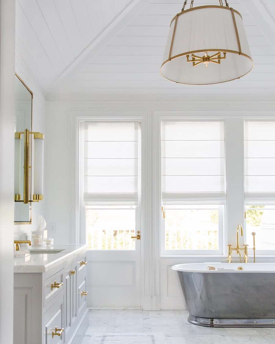 Bright bathroom with a vaulted white beadboard ceiling, gold accents, and a freestanding metallic tub, creating an elegant and airy retreat.