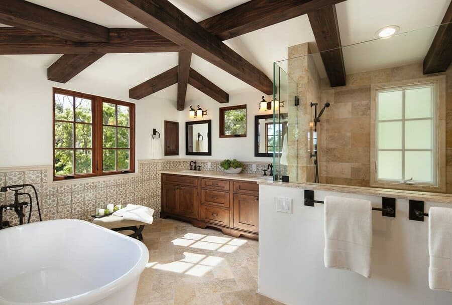 Spacious bathroom with dark wooden beams, a freestanding tub, and earthy tones, creating a warm and inviting rustic retreat.