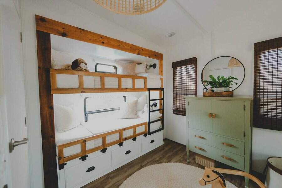 Stylish RV bedroom with built-in bunk beds, under-bed storage drawers, a green dresser, and natural wood accents for a cozy feel.