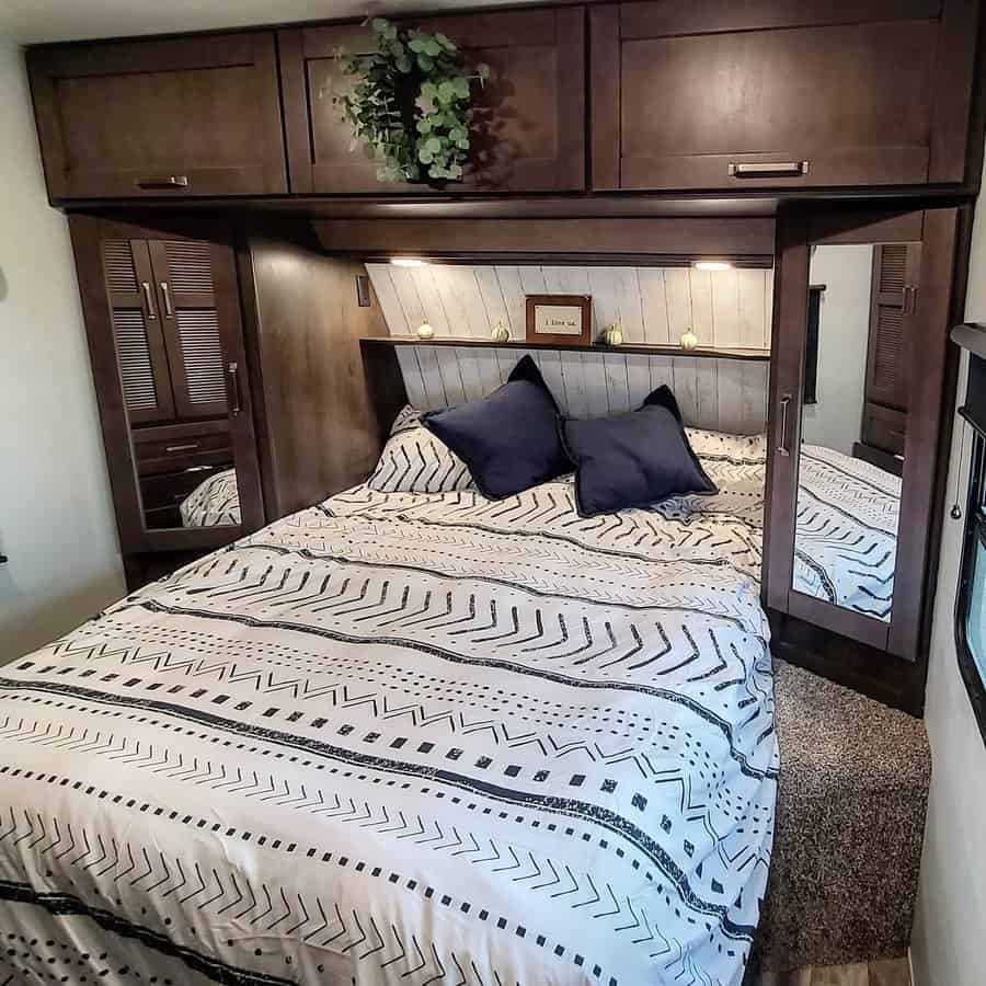 Cozy RV bedroom with dark wood finish and patterned bedding