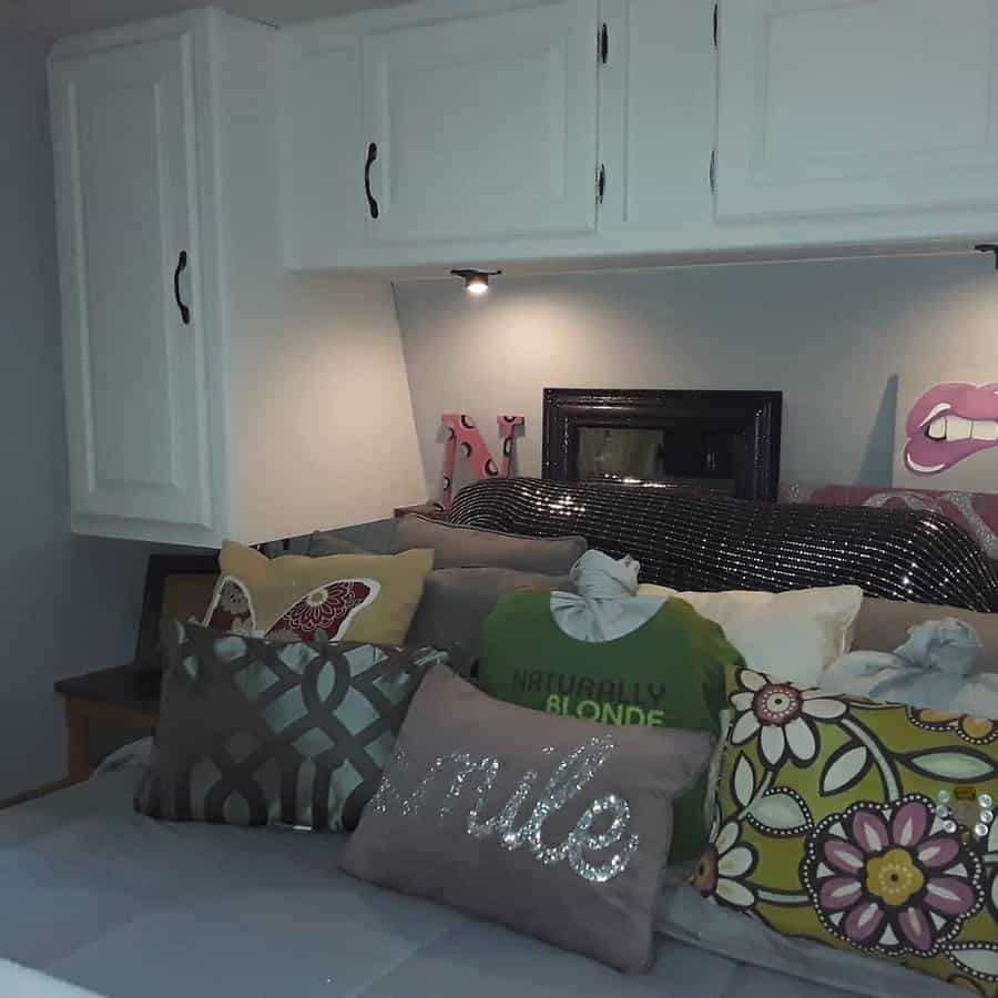 Whimsical RV bed with colorful pillows and overhead storage