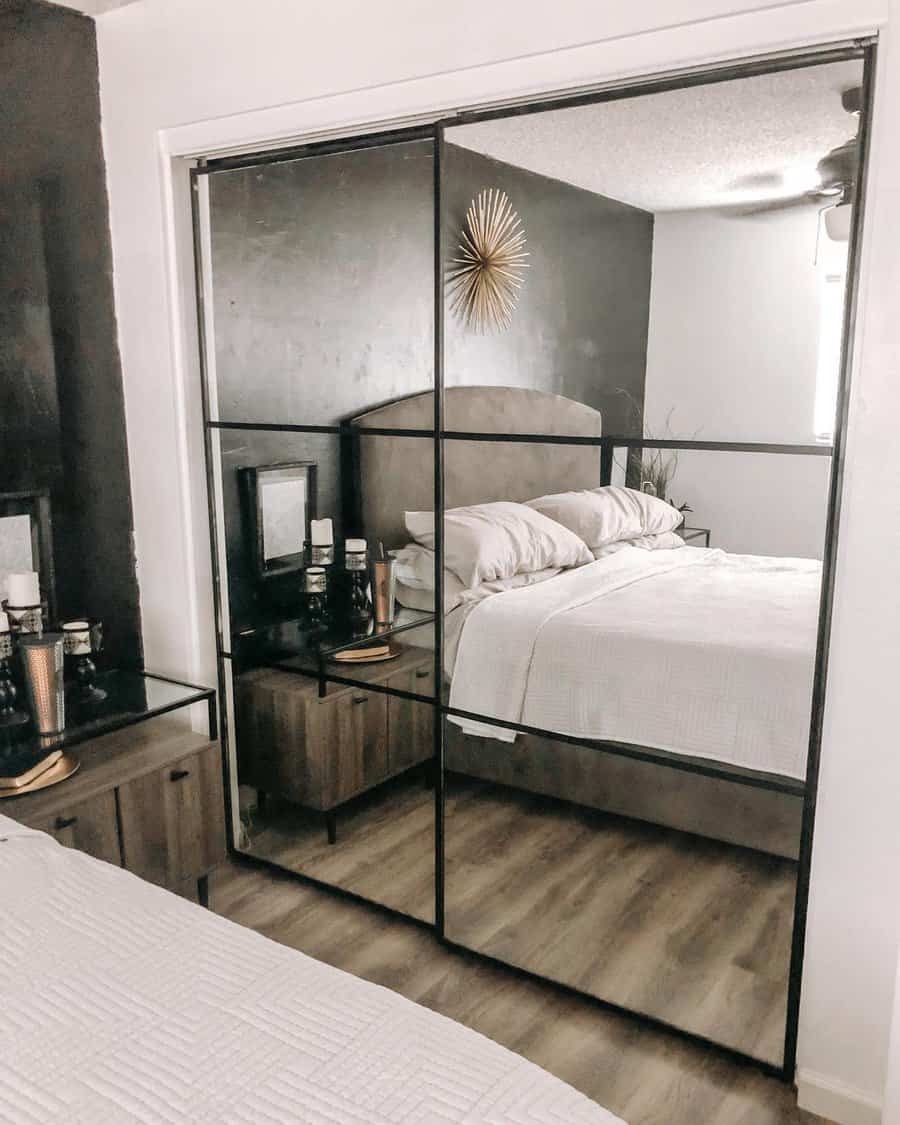 Bedroom with a bed, mirrored closet doors, dark accent wall, and modern decor