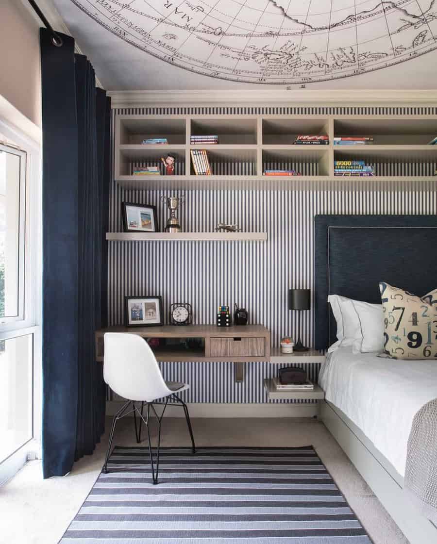 Elegant bedroom office with a floating wood desk, striped wallpaper, built-in shelves, and a globe ceiling mural for a unique touch