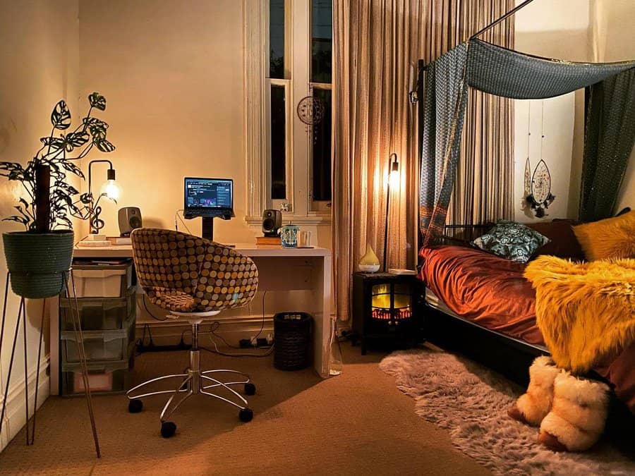 Cozy room with a bed, canopy, fluffy blankets, desk with computer, potted plant, and a small heater. Warm lighting creates a relaxing vibe