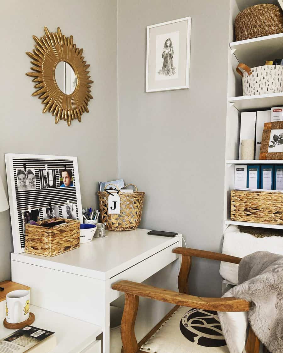 Cozy home office with a white desk, wooden chair, woven baskets, sunburst mirror, and bookshelves in a corner