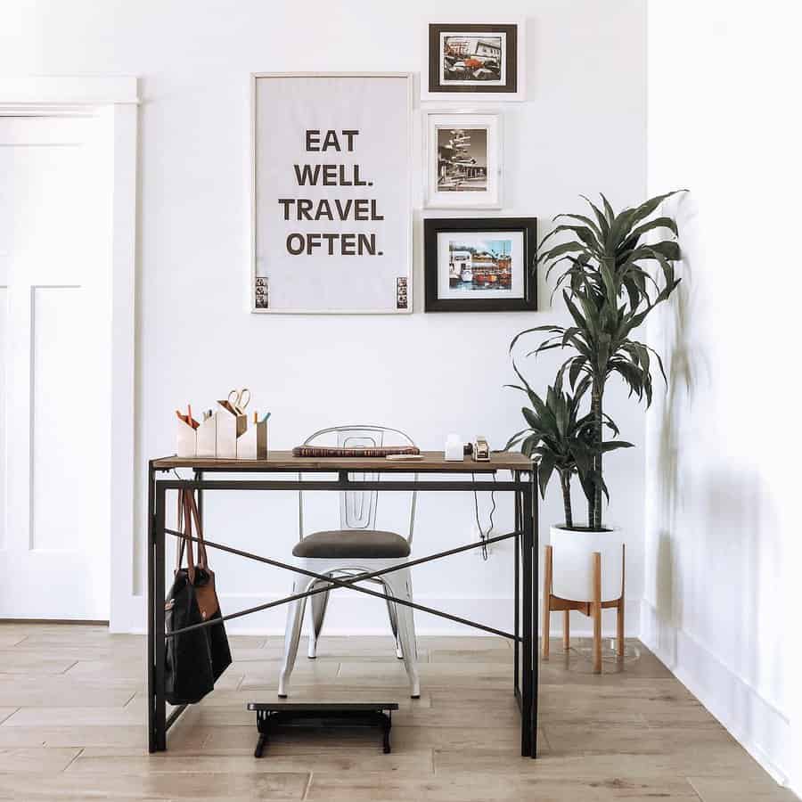 Minimalist office with a desk, chair, plant, and wall art reading "Eat Well, Travel Often" in neutral tones and wooden floor