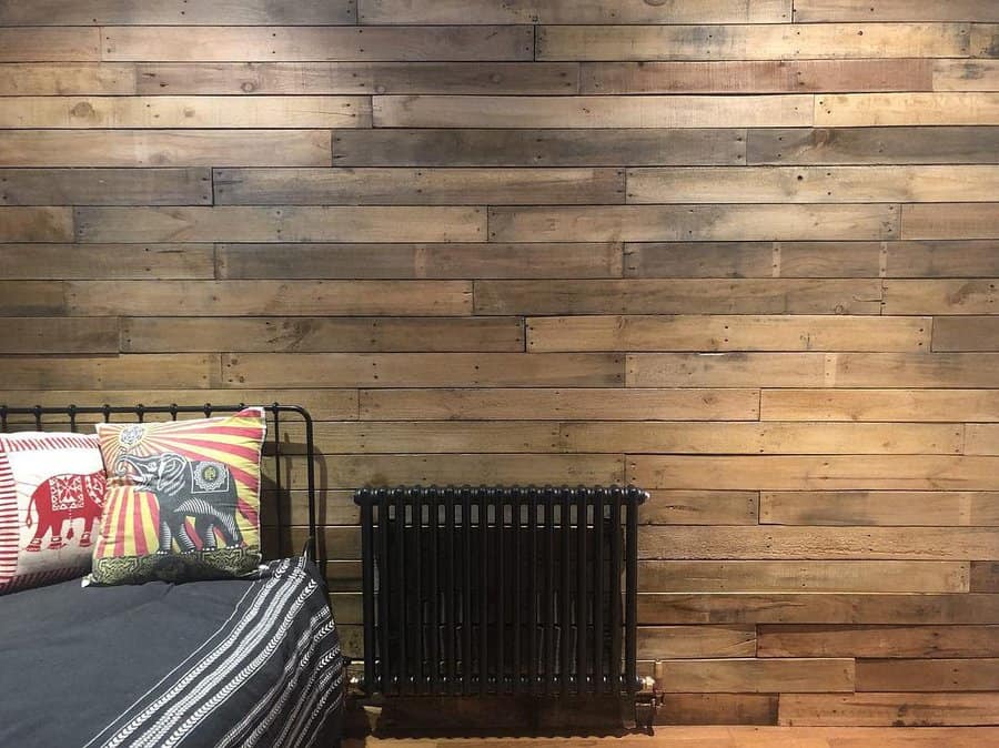 Bedroom with patterned bedding and a rustic pallet wall