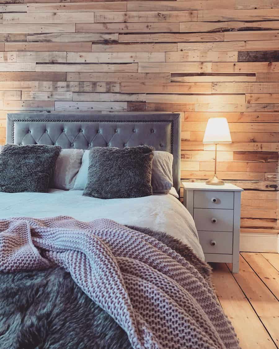 Warm bedroom with a plush headboard and rustic pallet wall