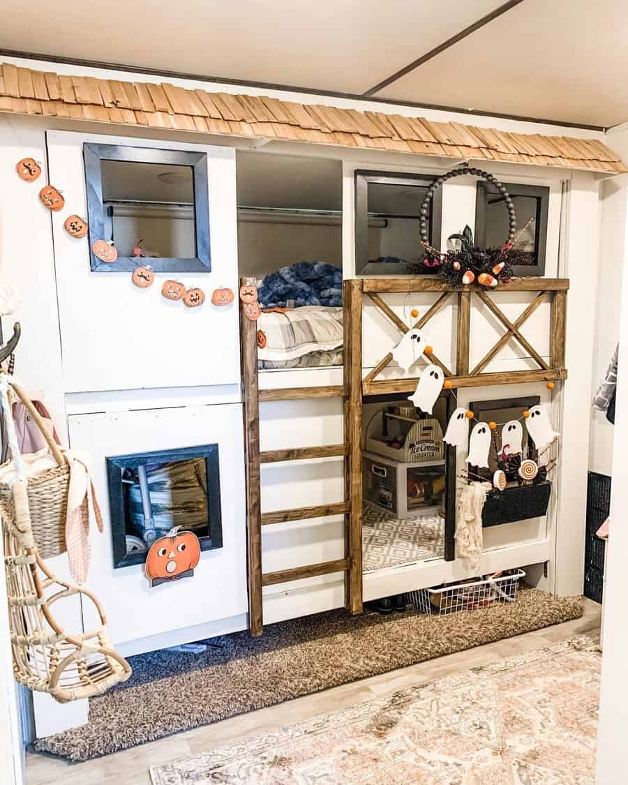 A playful RV bedroom with a Halloween-themed loft area, featuring ghost decorations, pumpkin accents, and rustic wooden details.