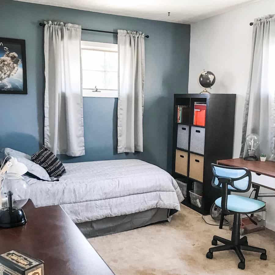 A cozy bedroom with blue walls, a neatly made bed, and a storage unit with fabric bins, creating an organized and functional space