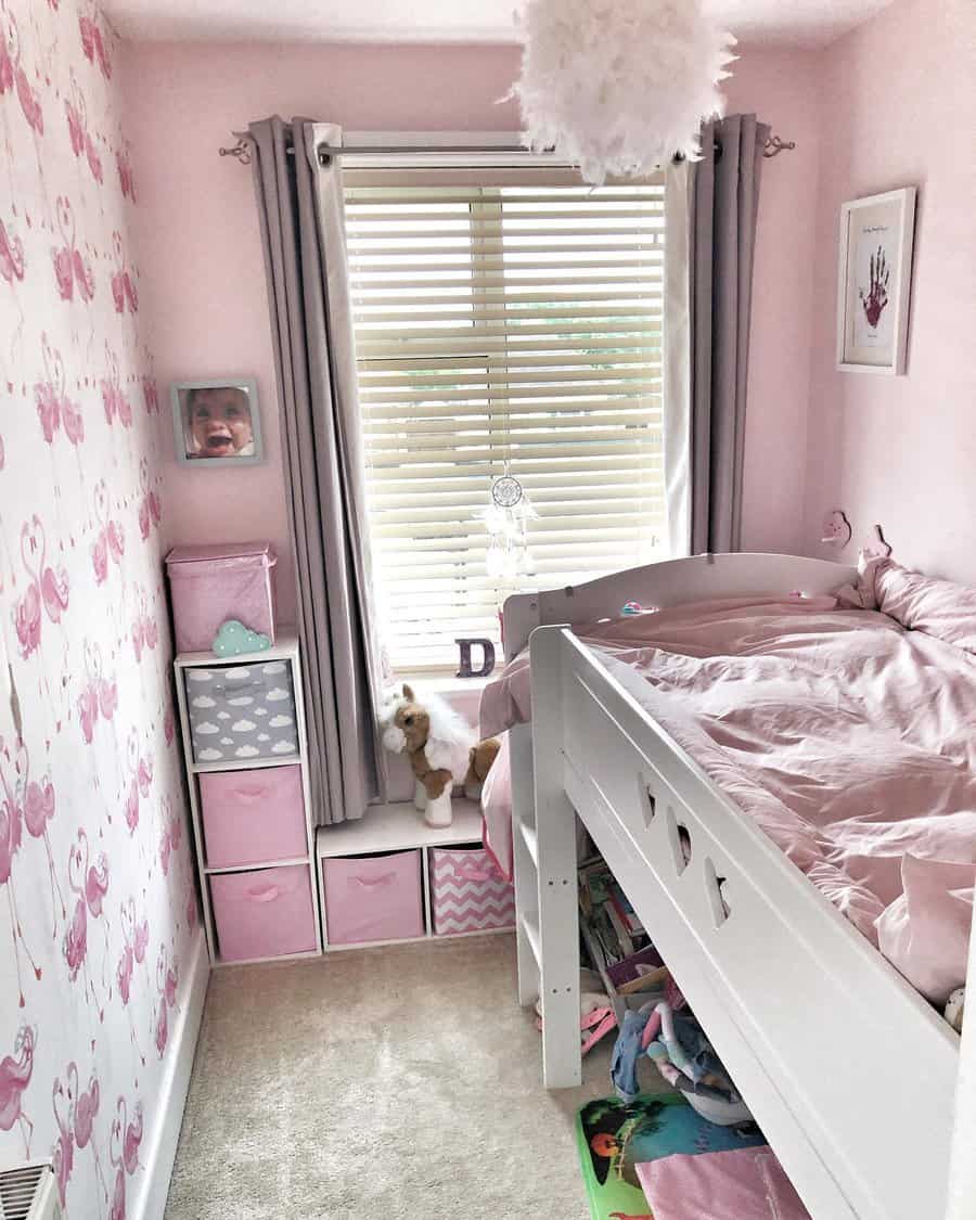 A charming pink-themed bedroom with a loft bed, under-bed storage, cube organizers, and soft decor for a cozy and organized small space