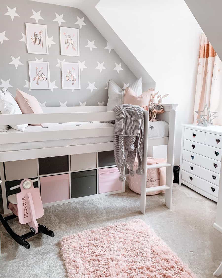 A stylish loft bed with under-bed cube storage, soft pink and gray decor, star-patterned walls, and cozy accents for a functional small bedroom