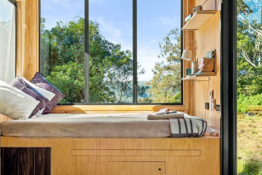 Cozy bed nook with forest view and shelf storage