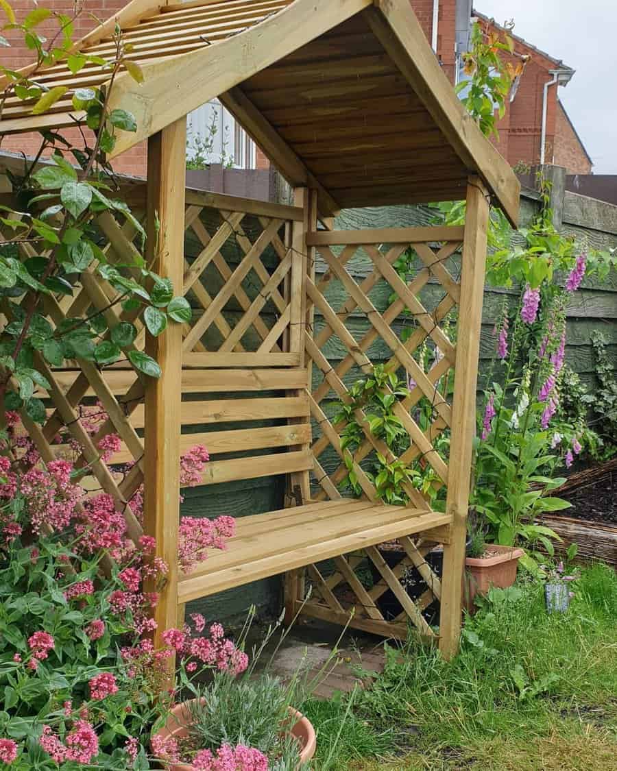 Wooden garden arbor with bench surrounded by flowers